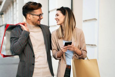 Alışveriş torbalarıyla mutlu genç bir çiftin portresi. İnsanlar tüketim ve yaşam tarzı konsepti satıyor.
