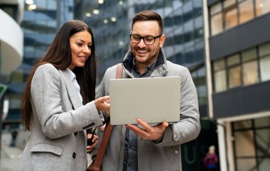 Genç başarılı iş adamları dışarıda çalışıyor ve konuşuyorlar.