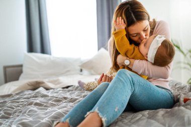 Anne ve bebek evde oynayıp gülümsüyor. Mutlu aile.