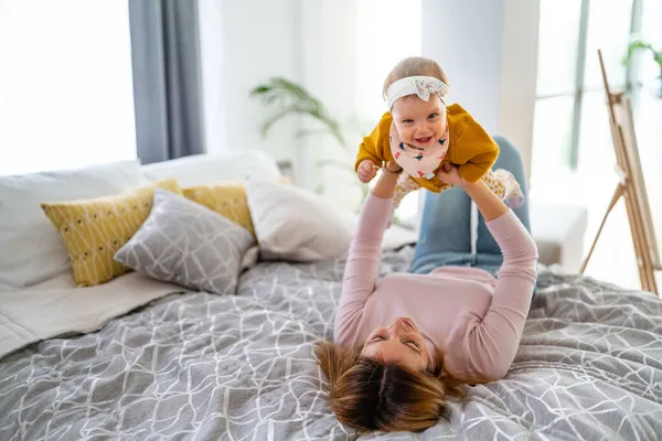 Anne ve bebek evde oynayıp gülümsüyor. Mutlu aile.