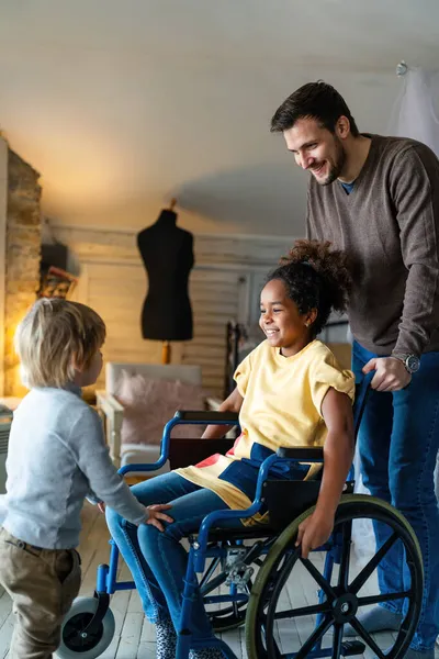 幸せな多民族の愛情の家族 家で車椅子の障害のある女の子を笑顔 — ストック写真