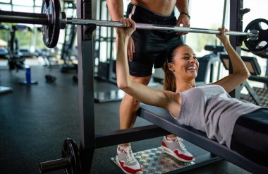 Genç bir antrenör, bir kadının spor salonunda çalışmasına yardım ediyor. Sağlıklı yaşam tarzı spor insanları konsepti