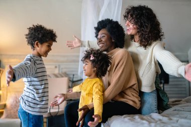 Mutlu çok ırklı aile evde birlikte vakit geçiriyor. Eşcinsel çift çocukları mutluluk kavramını sever