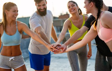 Bir grup mutlu zinde insan çatıda birlikte egzersiz yapıyor. Spor, sağlıklı yaşam konsepti