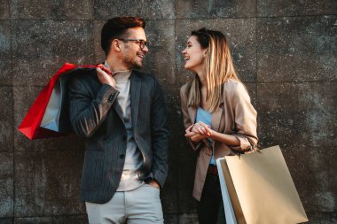 Alışveriş torbalarıyla mutlu genç bir çiftin portresi. İnsanlar tüketim ve yaşam tarzı konsepti satıyor.