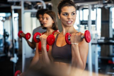 Spor salonunda sağlıklı kalmak için egzersiz yapan bir grup fit insan.