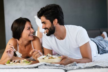 İyi sabahlar. Yatakta sağlıklı bir kahvaltı. Genç ve güzel bir çift birlikte vakit geçiriyorlar.