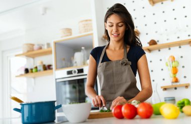 Mutlu, güzel, neşeli kadın, mutfakta sağlıklı yemekler yapıyor..