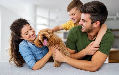 Mutlu genç aile eğleniyor, evde köpeklerle oynuyorlar.
