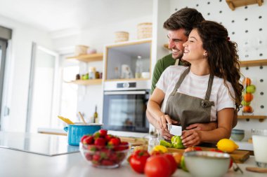 Genç mutlu çift evlerindeki mutfaklarında sağlıklı bir yemek hazırlıyor.