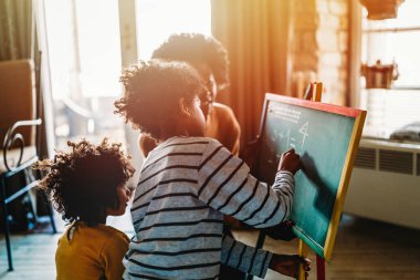 Mutlu siyah çocuklar anneleriyle matematik öğreniyor, öğretmenleri evde. Aile eğitimi mutluluk konsepti