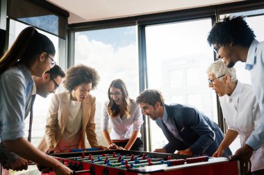 İş adamları birlikte harika vakit geçiriyorlar. Meslektaşlar ofiste masa futbolu oynuyor.