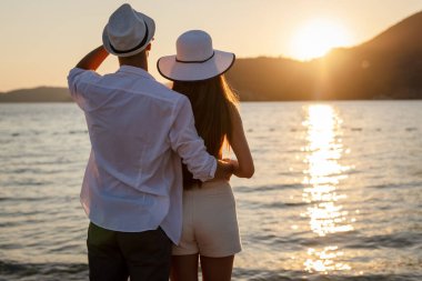 Güzel kumsalda yürüyen, yaz tatilinin tadını çıkaran çekici bir çift.