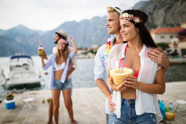 Bir grup arkadaş sahilde eğleniyor ve kokteyl içiyor.