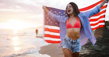 Mutlu kadın gülümseyip plajda koşarken bağımsızlık gününü kutluyor ve Amerika 'da özgürlüğün tadını çıkarıyor.
