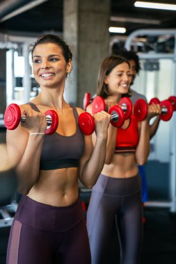 Spor salonunda egzersiz yapan bir grup sağlıklı genç.