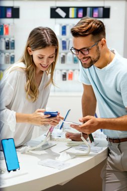 Mobil dükkanından yeni akıllı telefon alan mutlu gençler. Teknoloji Mutluluğu Cihaz Alışverişi