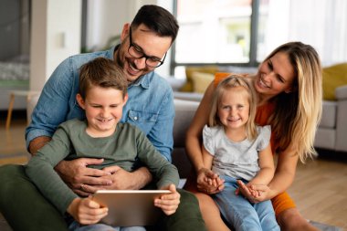 Mutlu genç aile evde eğleniyor. Çocuklu aileler tablet kullanıyor. İnsanlar mutluluk kavramını sever.