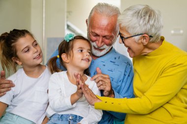 Mutlu büyükanne ve büyükbabalar evde torunlarıyla eğleniyor.
