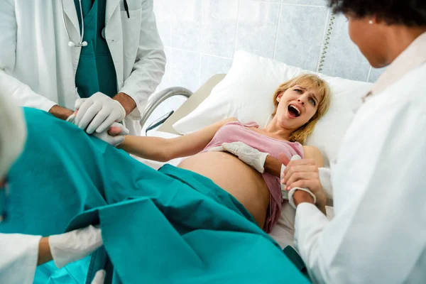 Woman giving birth in labor room of hospital. Doctor, support people concept