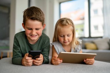 Küçük kız ve oğlan video izliyor ya da dijital cihaz tabletlerinde oyun oynuyorlar, akıllı telefon. Çocuklar dijital bağımlılık kavramı.