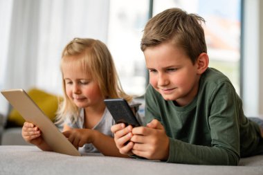 Küçük kız ve oğlan video izliyor ya da dijital cihaz tabletlerinde oyun oynuyorlar, akıllı telefon. Çocuklar dijital bağımlılık kavramı.