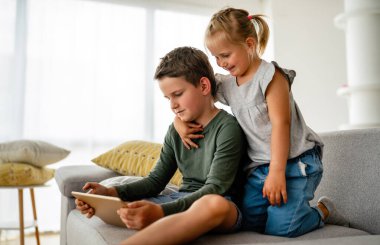 Küçük kız ve oğlan video izliyor ya da dijital cihaz tabletlerinde oyun oynuyorlar, akıllı telefon. Çocuklar dijital bağımlılık kavramı.
