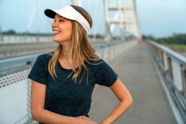 Genç, mutlu, zinde bir kadın şehirde antrenman yaptıktan sonra dinleniyor.