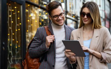 Başarılı iş arkadaşları dijital cihazlar üzerinde birlikte çalışıyorlar. İş adamları şehir konsepti üzerinde çalışıyor