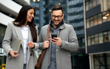 Şehirde gülümseyen genç iş adamları konuşuyor. İş başarısı insanlar konsepti