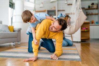 Mutlu genç aile eğleniyor ve evde birlikte oynuyorlar. Ebeveynlik, çocukluk, mutluluk kavramı