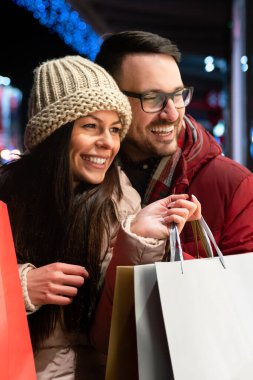Mutlu insanlar Noel alışverişi yaparken süslenmiş sokakta dikiliyorlar. Satış, xmas çift konsepti