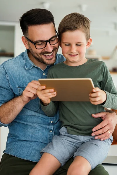 E- öğrenim için dijital tablet kullanan baba ve çocuğun portresi. Eğitimde evde eğitim veren dijital cihaz çocuk kavramı.