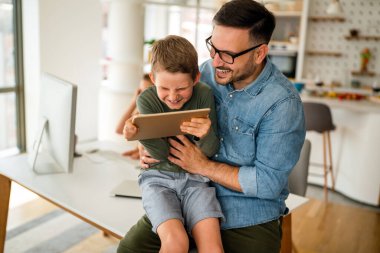E- öğrenim için dijital tablet kullanan baba ve çocuğun portresi. Eğitimde evde eğitim veren dijital cihaz çocuk kavramı.
