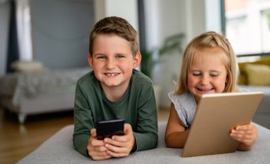 Küçük kız ve oğlan video izliyor ya da dijital cihaz tabletlerinde oyun oynuyorlar, akıllı telefon. Çocuklar dijital bağımlılık kavramı.