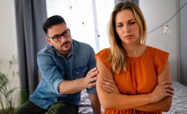 Sad pensive couple thinking of relationships problems sitting on sofa, conflicts in marriage, upset couple after fight dispute, making decision of breaking up get divorced