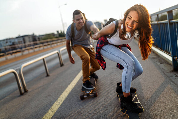 Group of happy friends hang out together and enjoying skateboard outdoors.