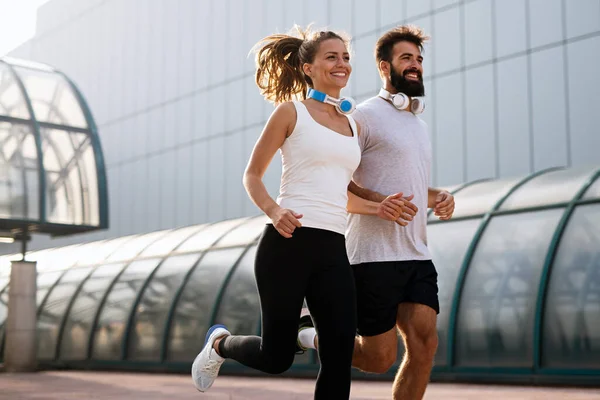 Happy young runner couple exercising outside as part of healthy lifestyle. People sport running concept