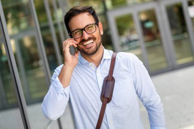 Ofisin önünde akıllı telefon kullanan başarılı bir iş adamı. Teknoloji işi mutluluk kavramı.