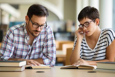 Bir üniversite kütüphanesinde birlikte çalışan mutlu bir öğrenci grubu. Eğitim insanları takım çalışması kavramı.