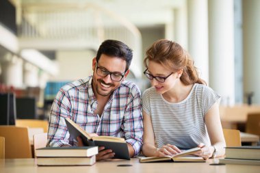 Öğrenciler kütüphanede okuyor. Gençler birlikte zaman geçirip birlikte öğreniyor..