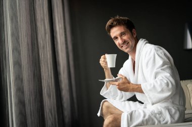 Bornozlu yakışıklı genç adam Spa Wellness Otel 'de çay içiyor ve dinleniyor.