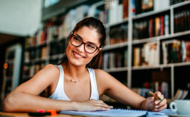 Kütüphanede okuyan mutlu genç bir kadının portresi. Eğitim eğitimi gençlik konsepti