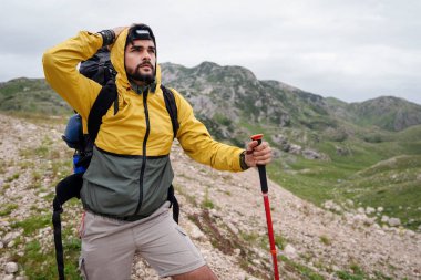 Sırt çantası ve yürüyüş direkleri olan yürüyüşçü dışarıdaki dağlara bakıyor.