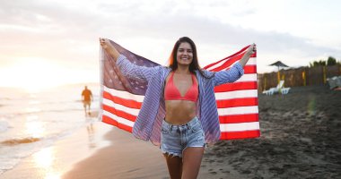 Mutlu kadın gülümseyip plajda koşarken bağımsızlık gününü kutluyor ve Amerika 'da özgürlüğün tadını çıkarıyor.