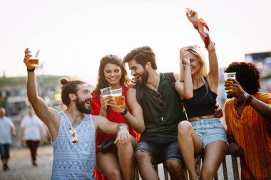 Bir grup mutlu genç açık hava müzik festivalinin tadını çıkarıyor.