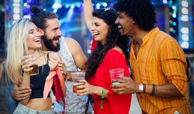 Bir grup mutlu genç açık hava müzik festivalinin tadını çıkarıyor.