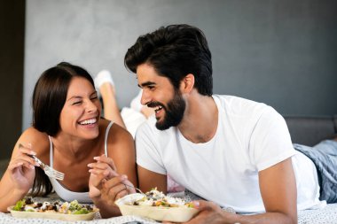 Genç beyaz çift yatakta romantik bir kahvaltı yapıyor..