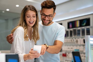 Mobil dükkanından yeni akıllı telefon alan mutlu gençler. Teknoloji Mutluluğu Cihaz Alışverişi