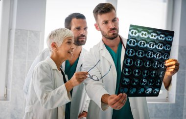 Bir grup doktor hastanedeki röntgenlere bakarak hastanın teşhisini tartışıyor.